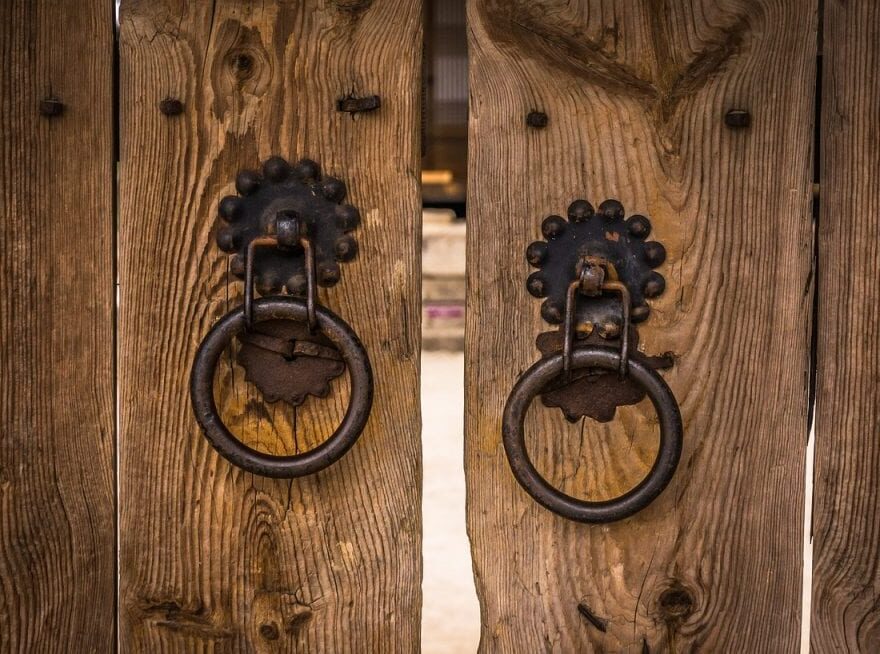 Opportunity Knocks header images shows a pair of closed wooden doors with a glimpse of what lies beyond.
