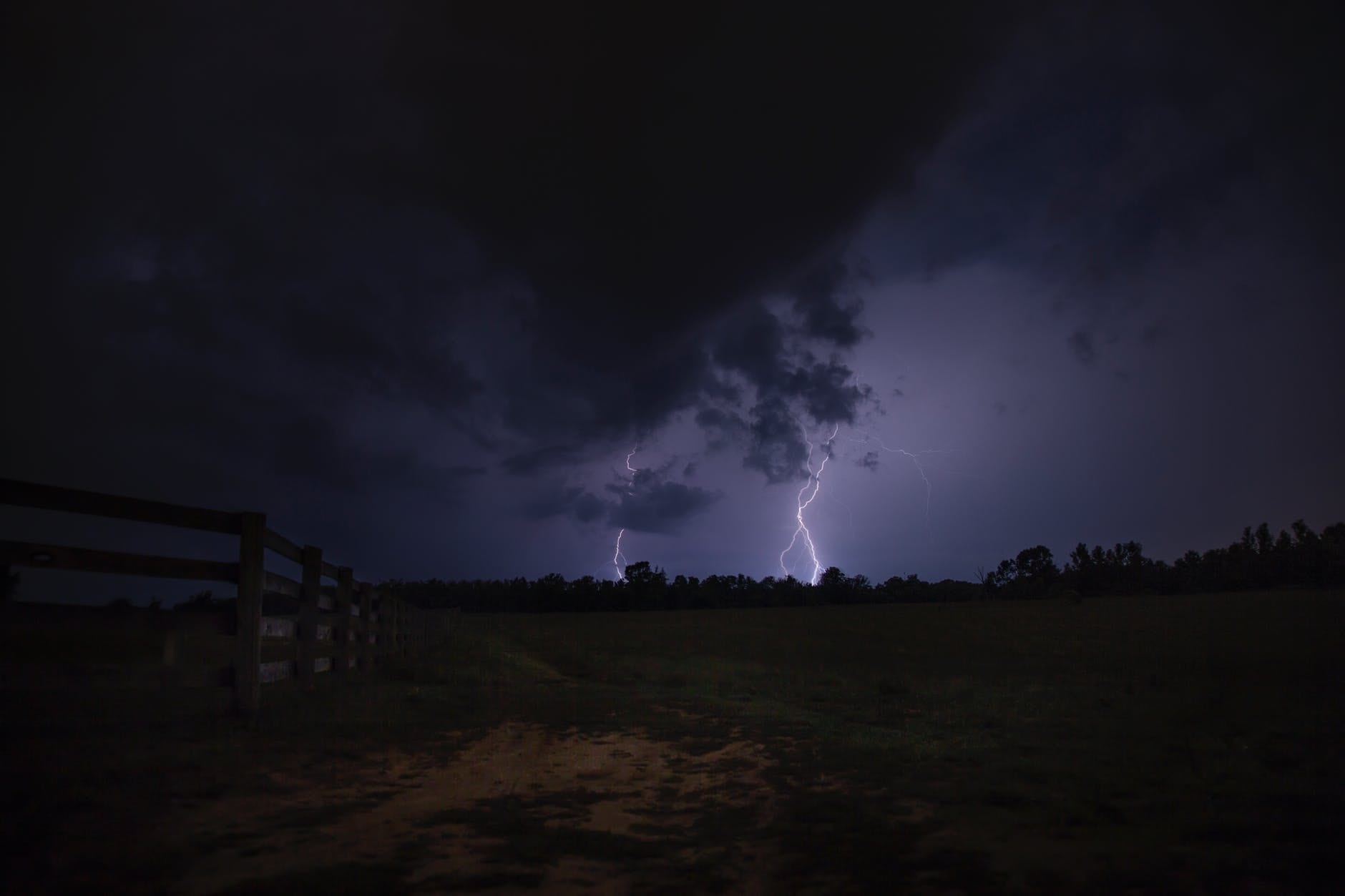 Let the universe surprise me header image shows a dark landscape being illuminated by lightning strikes on the horizon.