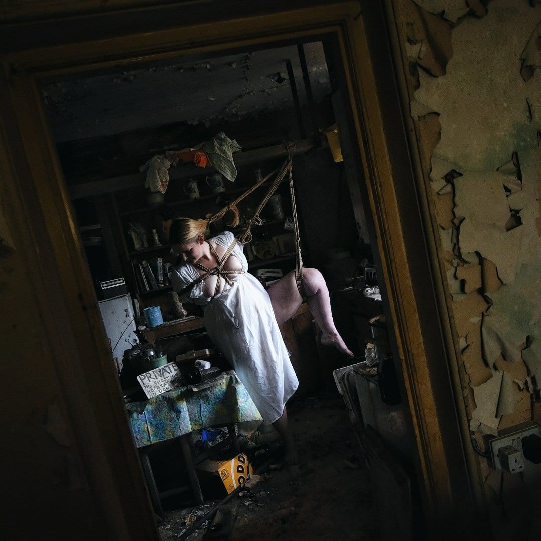 Just one more thing header image shows lady standing in a ripped white nightie in a derelict kitchen, tied to an overhead barby her hair, thigh and takeshi Kote harness.