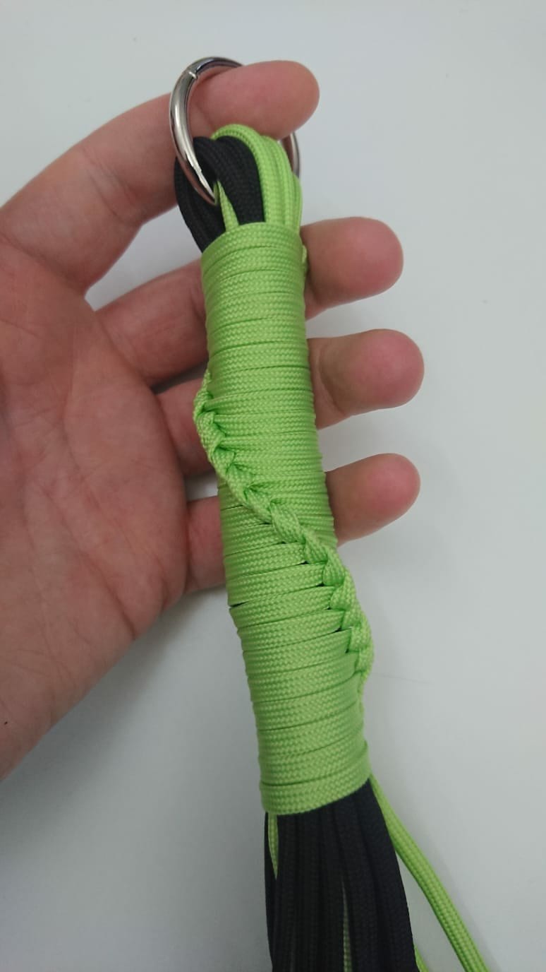 Picture shows the handle of a hand made flogger made from black and green paracord. This was one of the lessons I learned at Eroticon with thanks to kinkcraft.