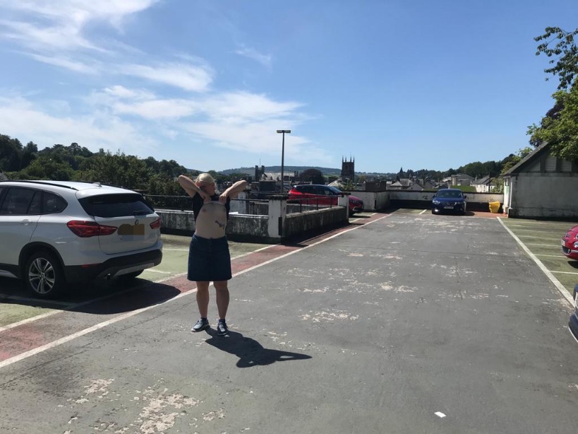 Lady, topless in a carpark, in the sunshine