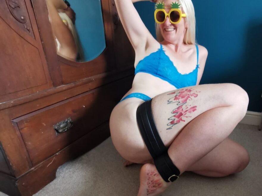 Tears escaping my eyes header shows blonde lady in pineapple sunglasses and bright blue lingerie leaning back while restrained in ankle to thigh cuffs.