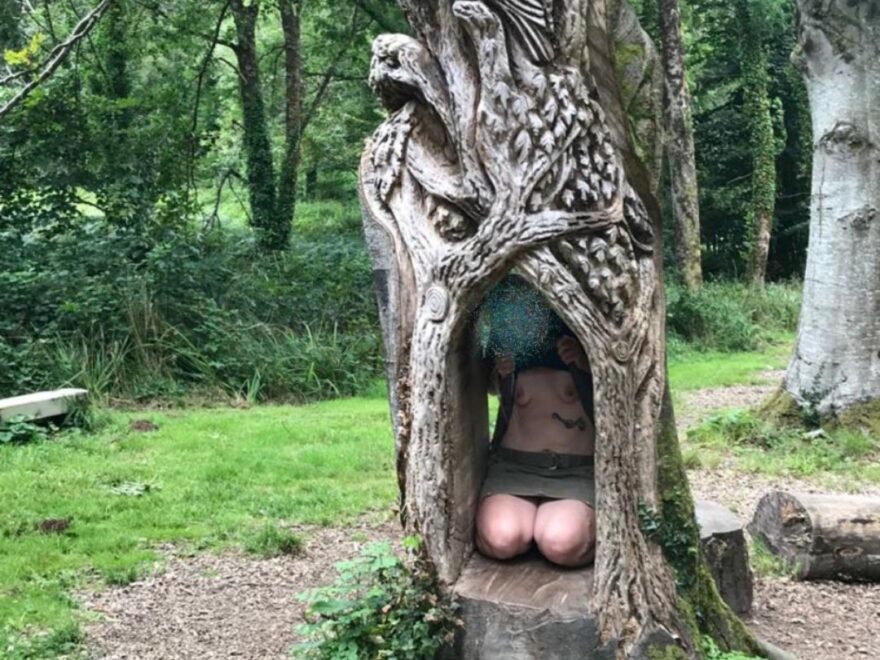 nature sculptures and breasts exposed by a lady kneeling inside a tree trunk