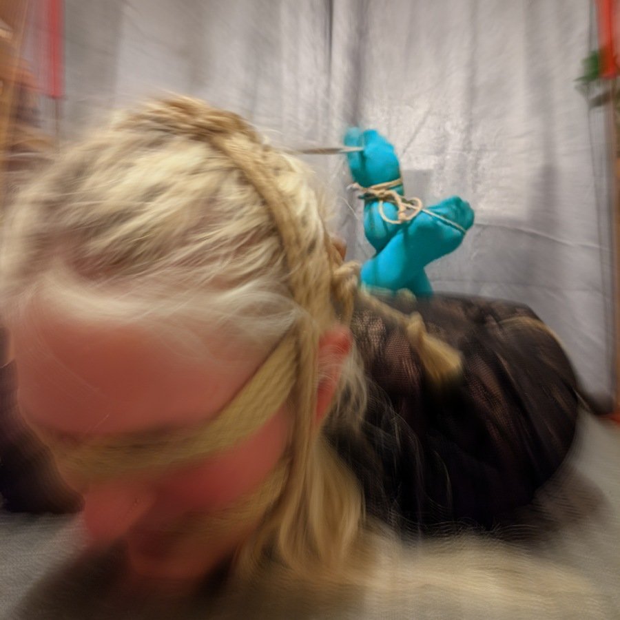 Life is a blur header lady hogtied and with face rope, edited to create a gently blurred effect.