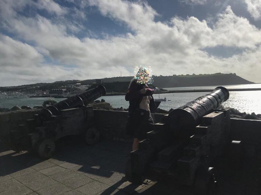 cannon fodder header image shows me exposing my breasts between two cannons pointing out over the water.