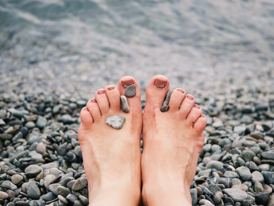 finding bare feet on a beach with stones between the toes