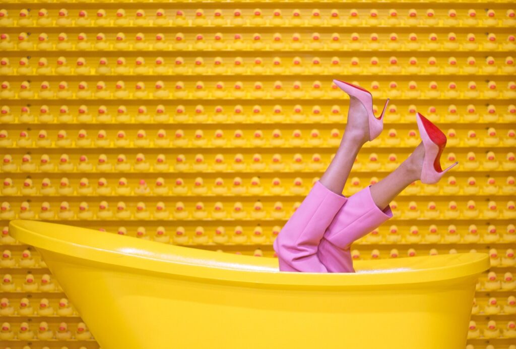 A fool in the bathtub with pink heels and trousers.