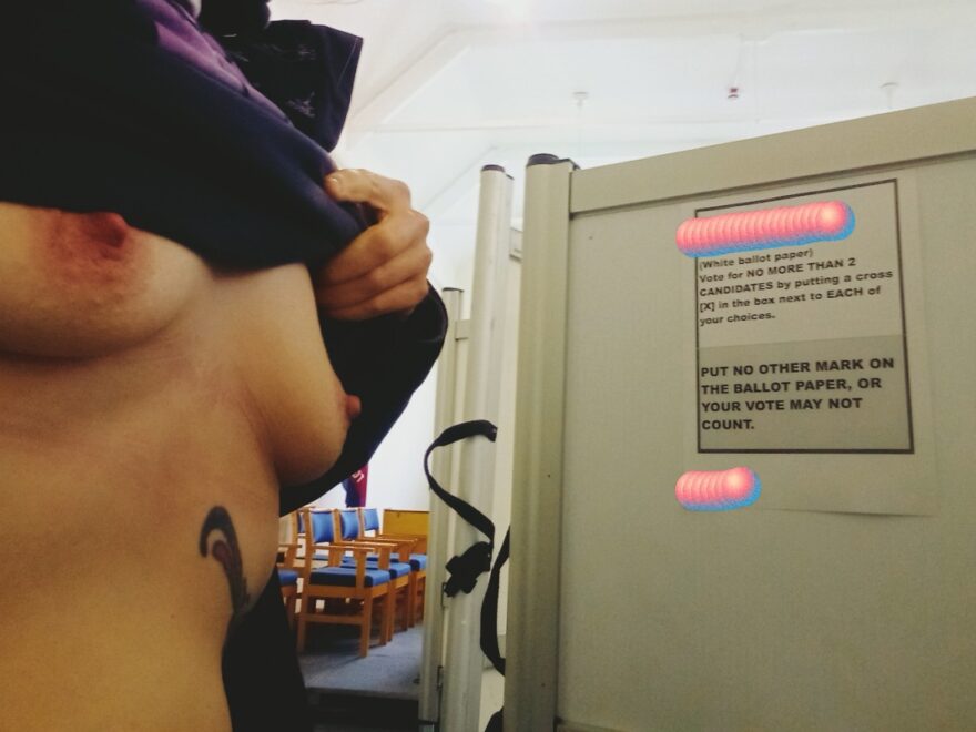 exposing my breasts in a polling booth while doing my civic duty. Poster behind me explains what voters need to do.