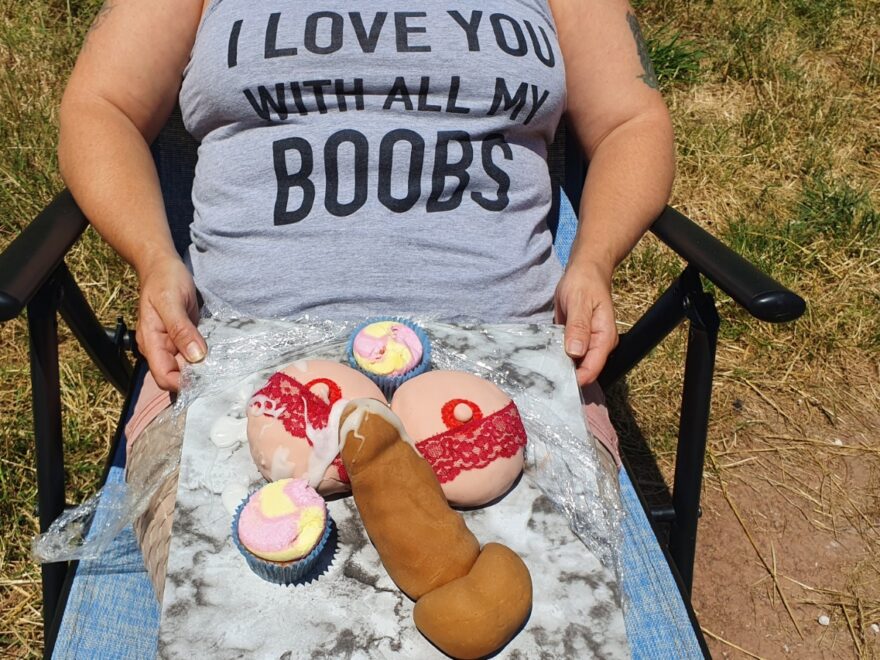 LovelyL sitting in her garden wearing a vest saying "I love you with all my boobs" while holding a birthday cake of boobs and a penis - complete with cum tribute.