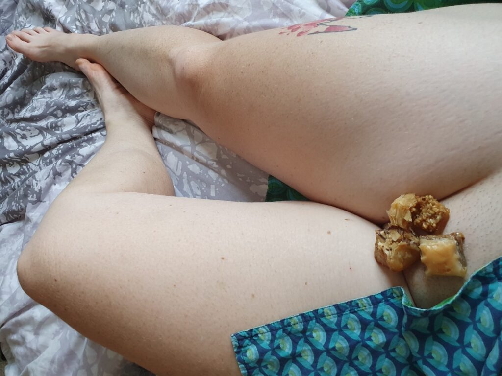 The barefoot sub finds herself in the sticky situation of having Baklava in place of pubic hair. Long bare legs stretched n the bed, SkirtFanatic skirt exposing her mons.