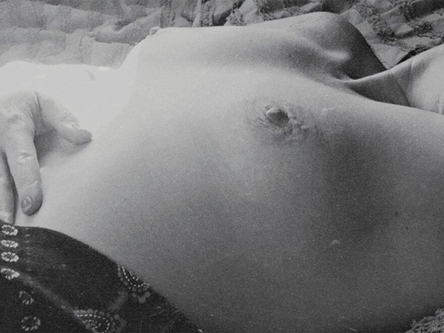 Feeling like I have pretty breasts as I lay out on the bed in the afternoon sun - black and white photo.