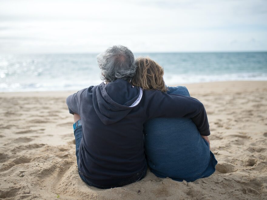 Couple showing a safe space mentality as they're hugging while sitting on the beach